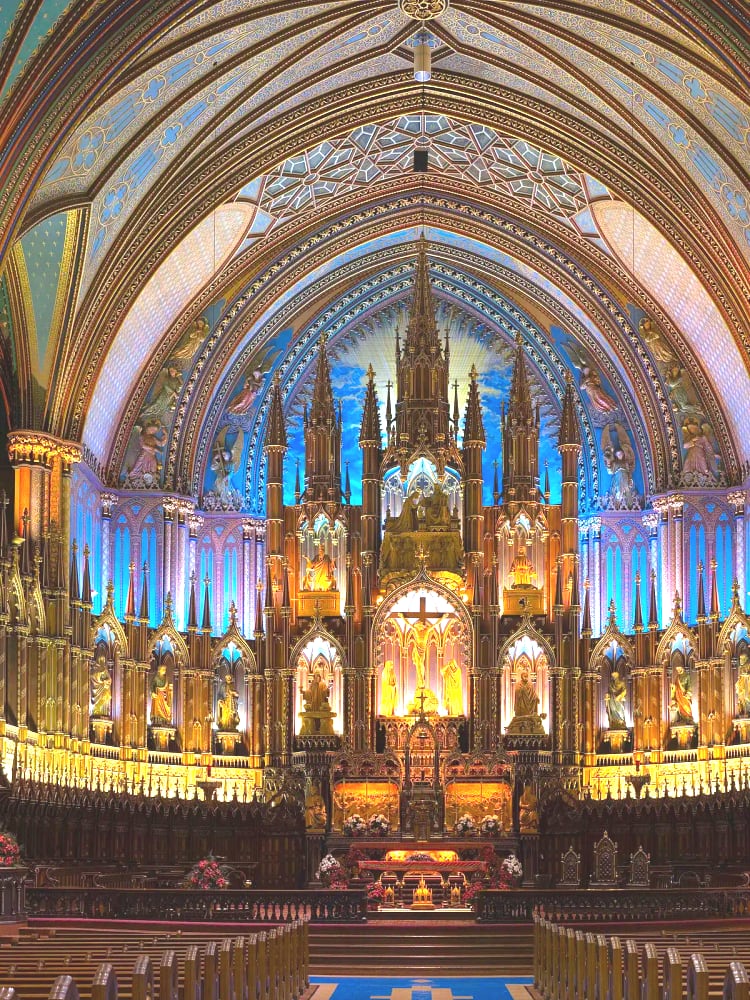 Basilique Notre-Dame de Montréal interior — royal-blue ceiling studded with gold stars, carved walnut reredos, rose-window stained glass. Gothic Revival 1829.